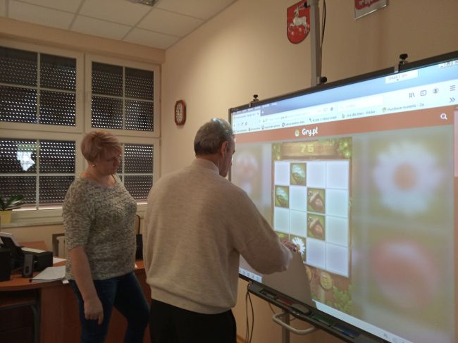 Na zdjęciu uczestniczk zajęć przy tablicy interaktywnej