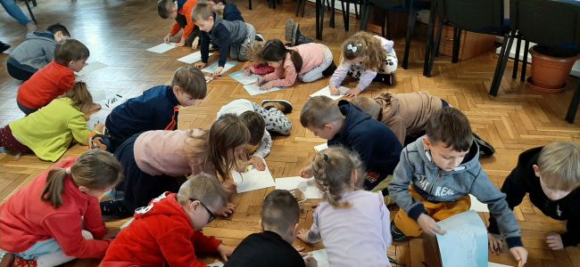 Dzieci siedzą na podłodze i rysują bałwany