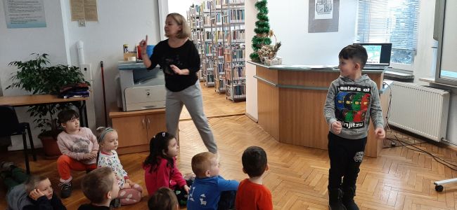 Dzieci grają w Kalambury. Jeden przedszkolak pokazuje hasło do odgadnięcia.