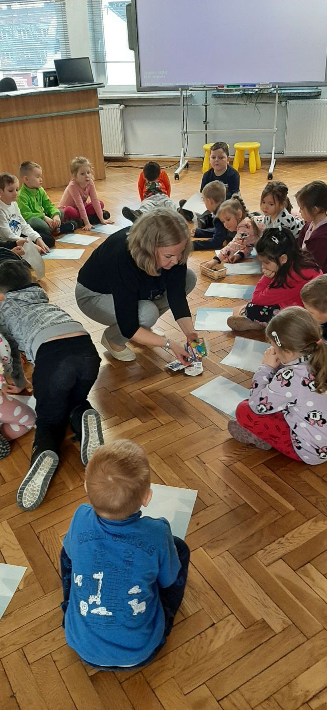 Dzieci siedzą na podłodze i rysują bałwany