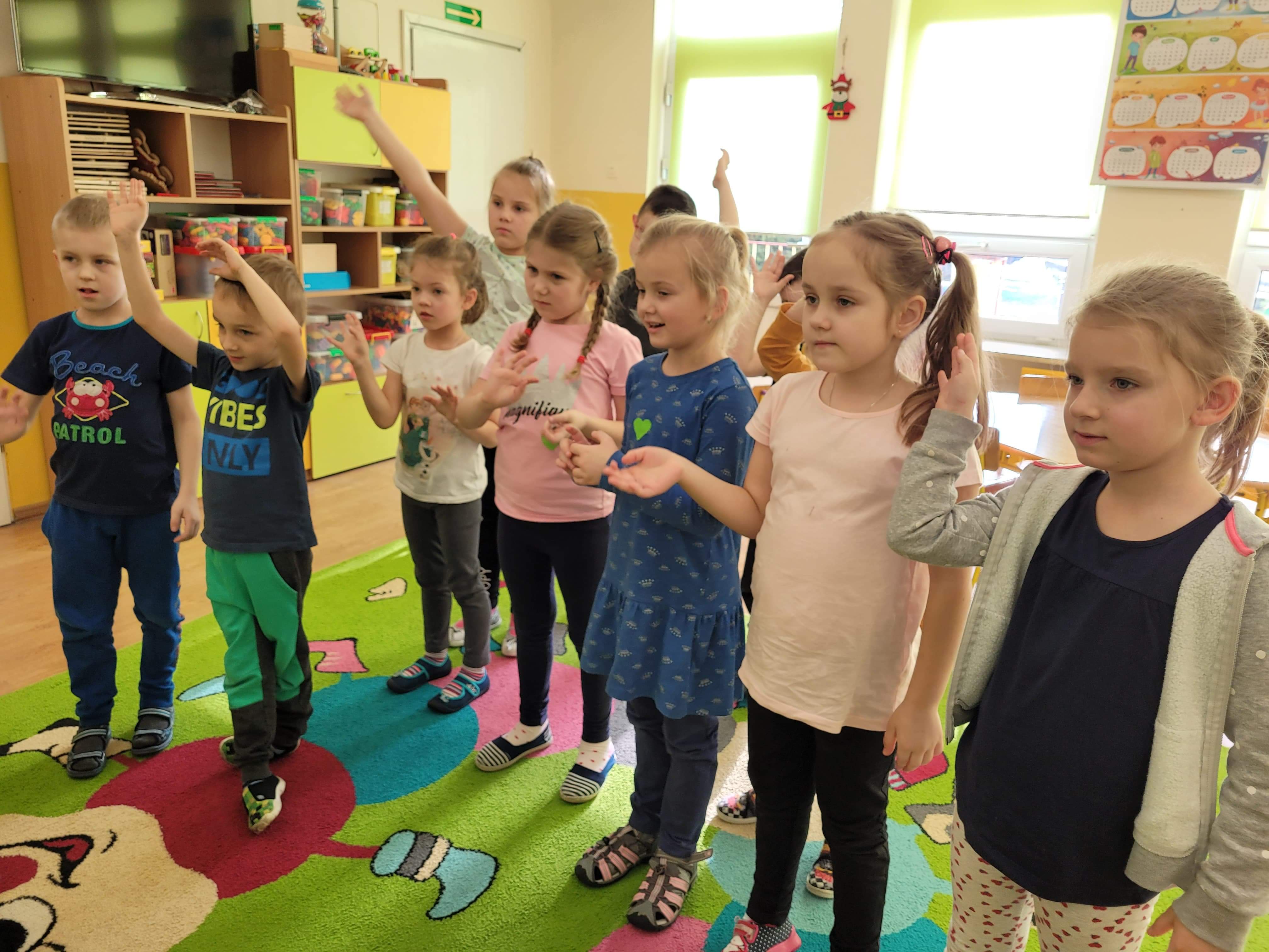 Dzieci podczas zabawy integracyjnej, naśladują prowadzacą zajęcia.