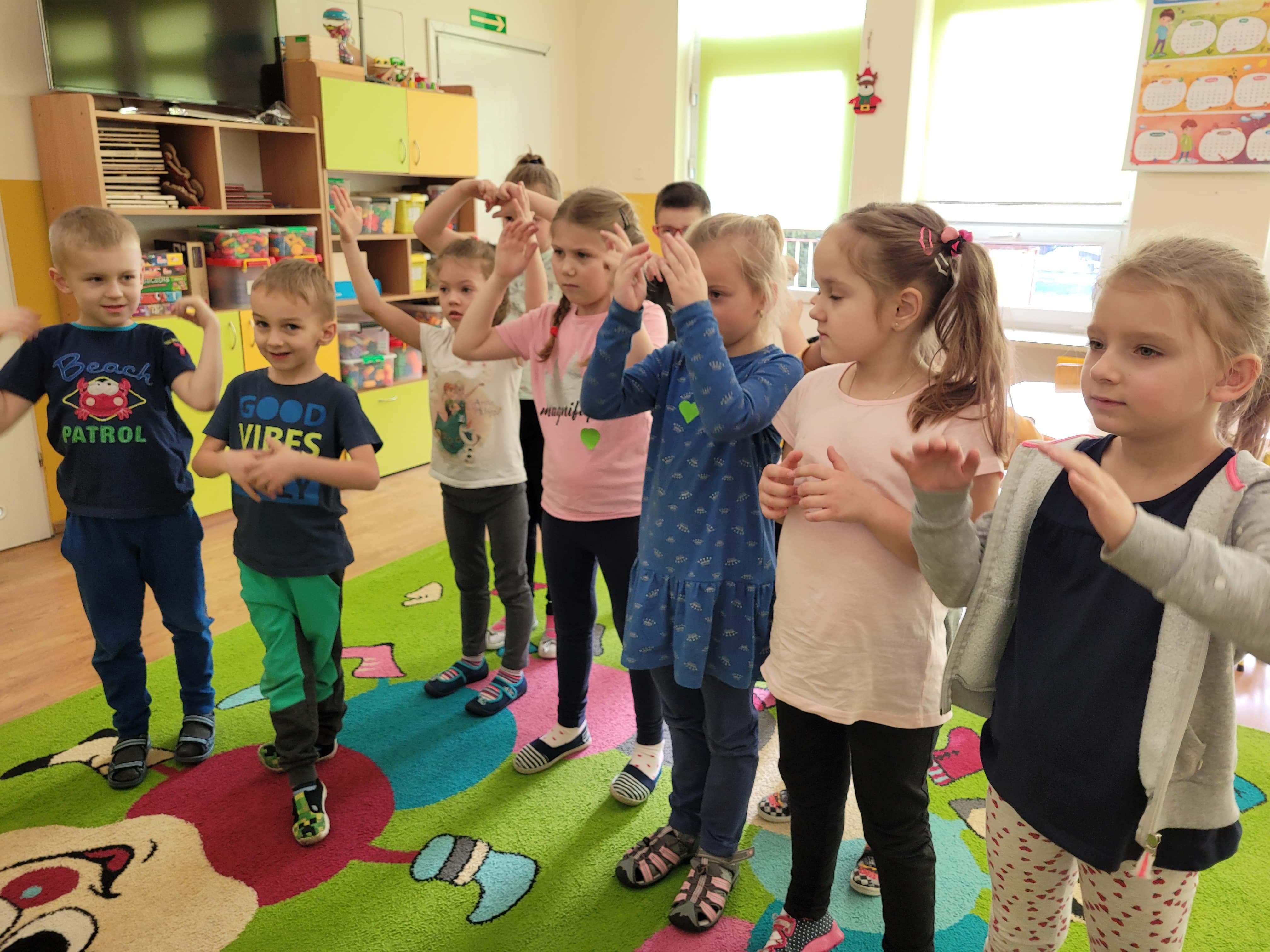 Dzieci podczas zabawy integracyjnej, naśladują prowadzacą zajęcia.