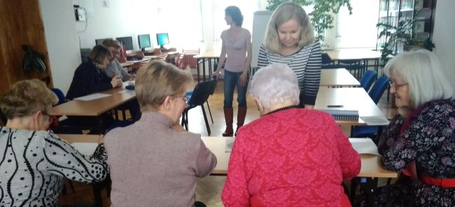 Prowadzące warsztaty tłumaczą seniorom wykonanie zadania.