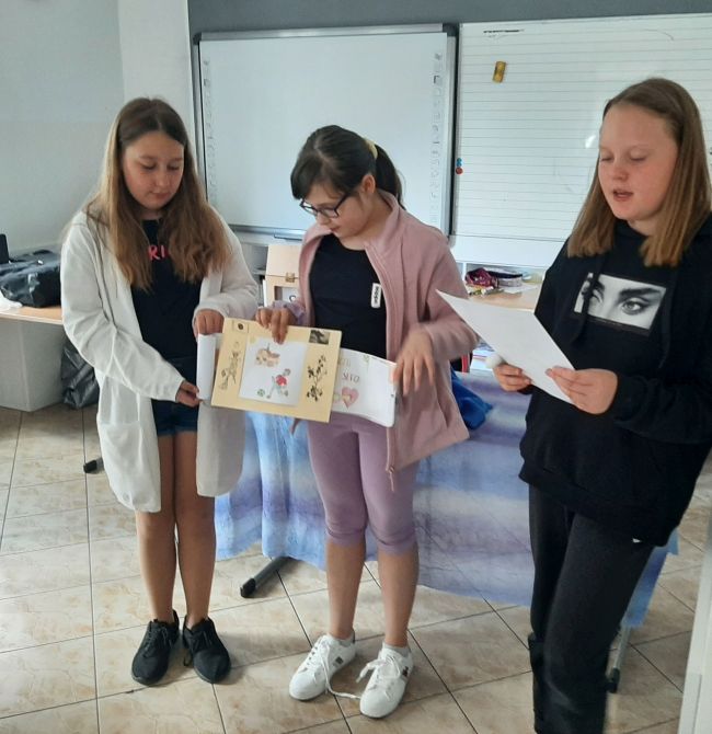 Trzy uczennice prezentują swoje opowiadanie metodą kamishibaj 