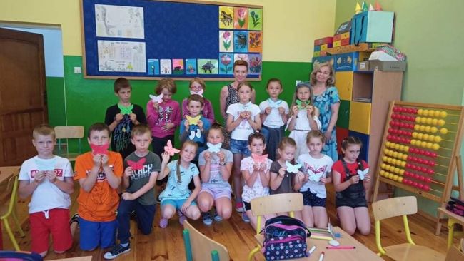 Zdjęcie grupowe. Uczestnicy spotkania. Nauczyciele bibliotekarze wraz z uczniami prezentującymi wykonane przez siebie prace plastyczne.