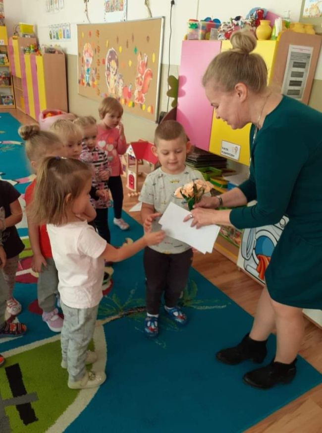 Przedszkolaki dziękują prowadzącej zajęcia i wręczaja laurkę.