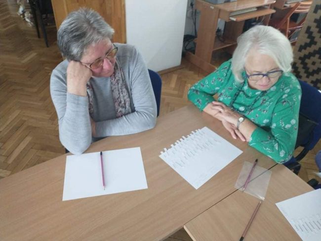 Zbliżenie na dwie seniorki rozwiązujące zadanie.