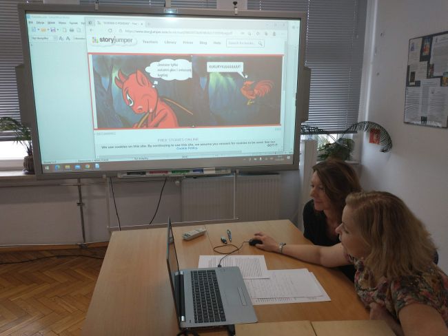 Prowadzące zajęcia on-line. W tle tablica interaktywna z książeczką-komiksem. Nauczyciele bibliotekarze prezentują legendę o “Piekiełku”, stworzoną w aplikacji StoryJumper.