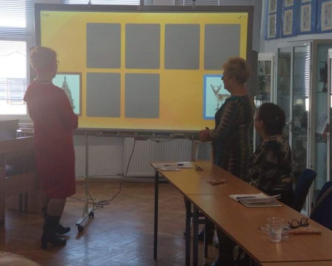 Dwie osoby stoją przy tablicy interaktywnej, grają w odszkiwanie I odsłanianie takich samych kart.