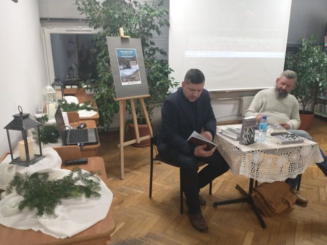 1 Na zdjęciu. Przy stoliku siedzą: autor spotkania Pan Robert Gmiterek (po prawej) oraz prowadzący spotkanie Pan Jarosław Joniec (po lewej). W tle ekran ze zdjęciami autorstwa Pana Roberta Gmiterka.