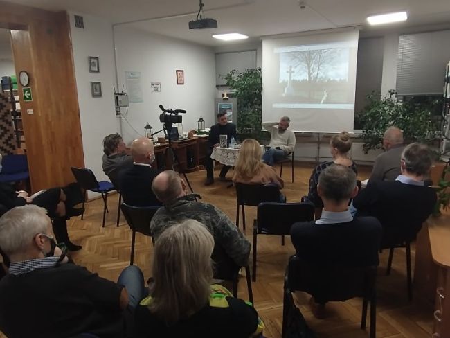 Na zdjęciu autor spotkania Pan Robert Gmiterek (po prawej), prowadzący spotkanie Pan Jarosław Joniec (po lewej) oraz uczestnicy. W tle ekran ze zdjęciami autorstwa Pana Roberta Gmiterka.