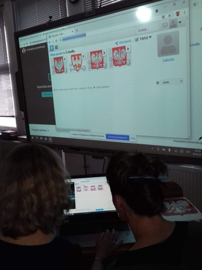 Nauczyciele bibliotekarze prowadzący zajęcia pracują przy laptopie. Na tablicy interaktywnej wyświetlone zadanie dla przedszkolaków