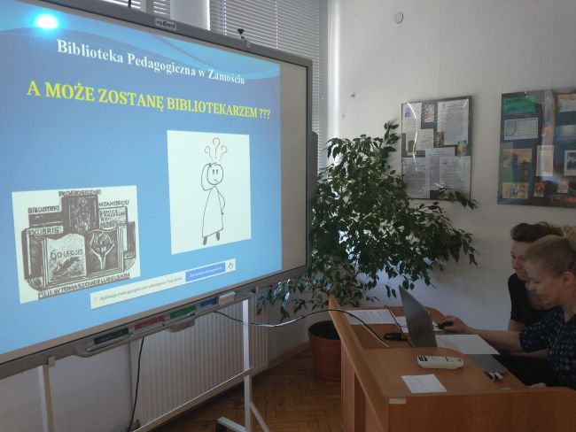 Na tablicy interaktywnej wyświelony tytuł zajęć “A może zostanę bibliotekarzem?” Nauczyciele bibliotekarze prowadzą zajęcia.