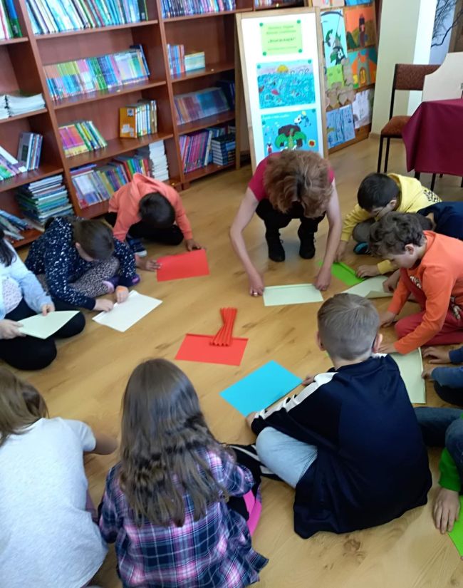 Uczniowie samodzielnie,  na podłodze wykonują papierowe wachlarze. 