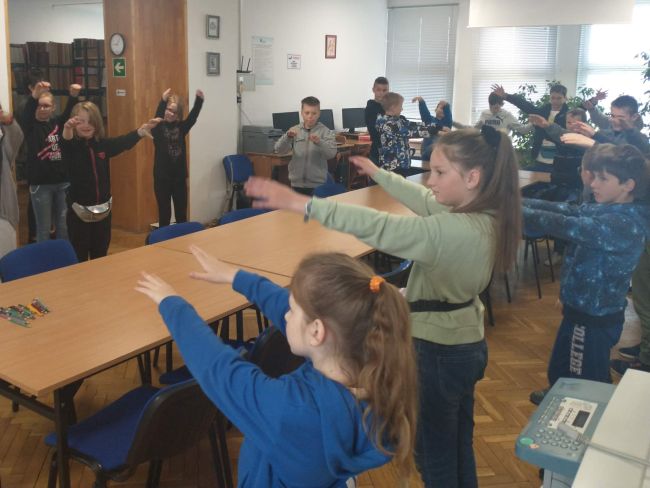 Uczniowie w postawie stojącej naśladują ruchy prowadzącej