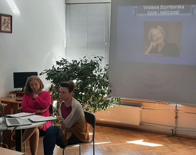Na zdjęciu dwie prowadzące. W tle prezentacja multimedialna.
