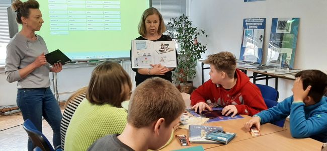 Prowadząca prezentuje książki. Uczniowie siedzą przy stolikach i oglądają kreatywne książki