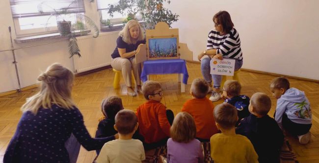 Praca plastyczna. Dzieci siedzą przy stole i kolorują motylki.