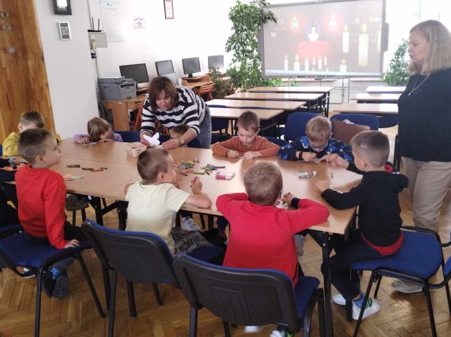 Praca plastyczna. Dzieci siedzą przy stole i kolorują motylki.