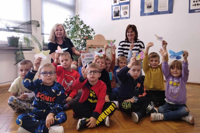 Zdjęcie grupowe przedszkolaków siedzących na podłodze.