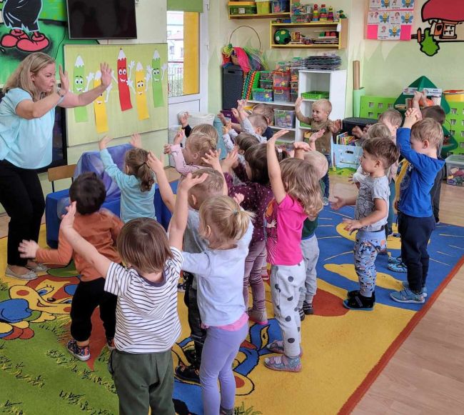 Zabawa ruchowa. Dzieci stoją i  naśladują prowadzącą zajęcia