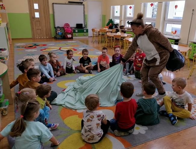 Prowadzącą przebraną za Misia czyta przedszkolakom opowiadanie o Misiu Tulisiu