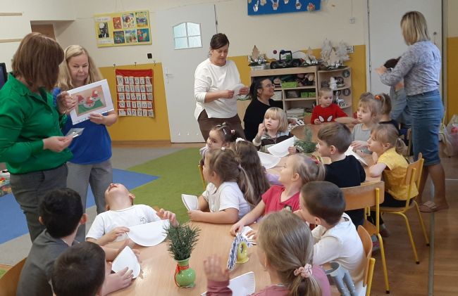Dzieci siedzą przy stolikach i  wykonują pracę plastyczną