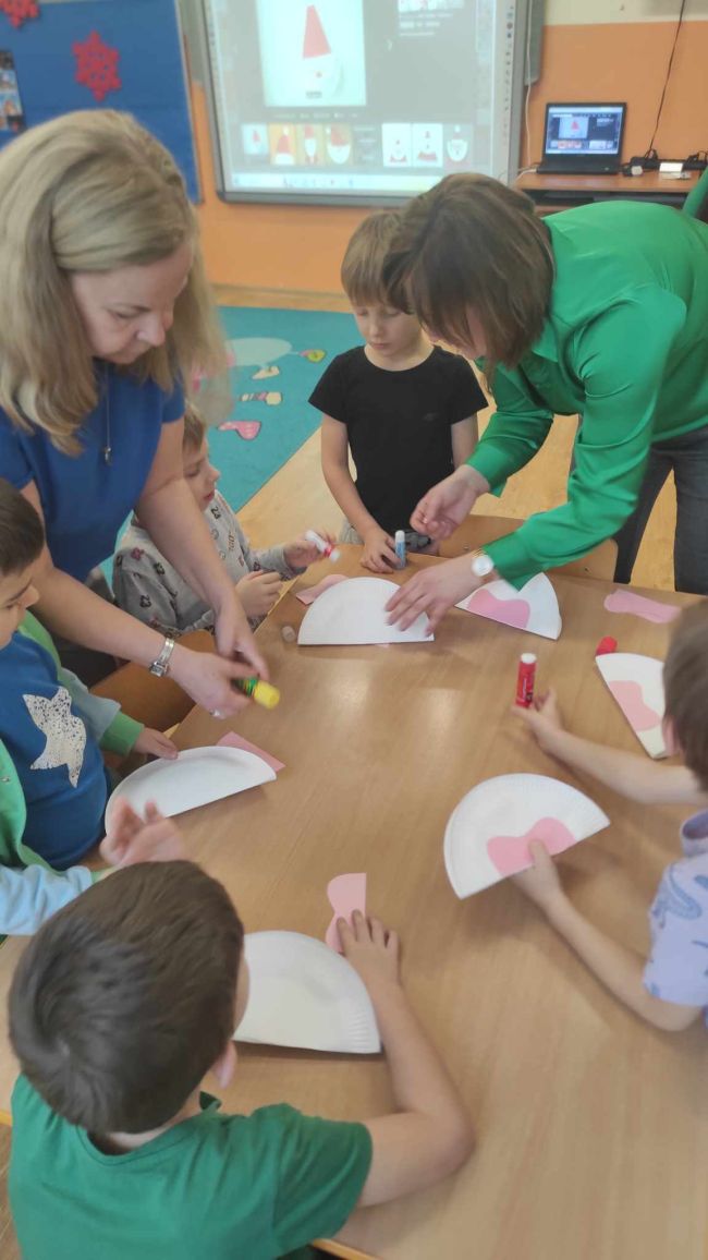 Dzieci siedzą przy stolikach i  wykonują pracę plastyczną