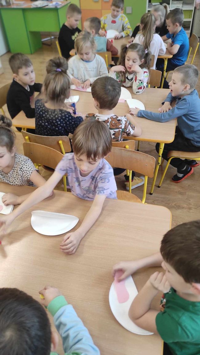 Zdjęcie zbiorowe z zajęć. Prowadząca czytają historię metodą kamishibai.