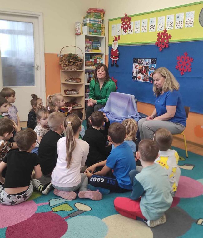 Dzieci siedzą przy stolikach i  wykonują pracę plastyczną