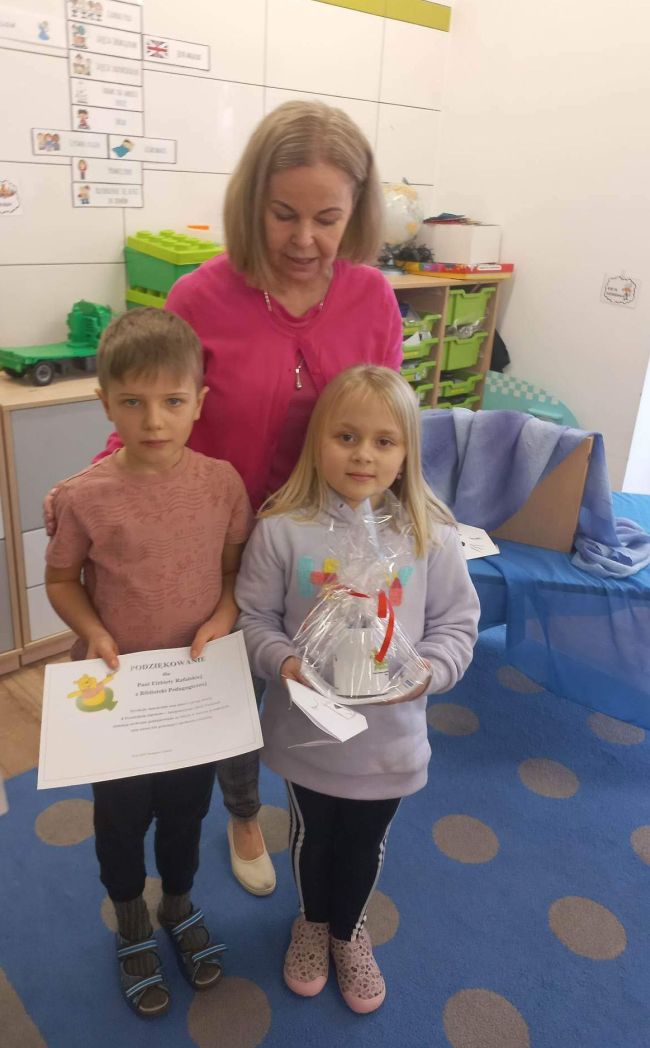 Dwoje dzieci wręcza podziękowanie prowadzącej zajęcia