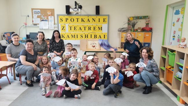 Na zdjęciu grupa przedszkolaków z wykonanymi przez siebie pracami wraz z opiekunami i prowadzącymi zajęcia nauczycielami bibliotekarzami