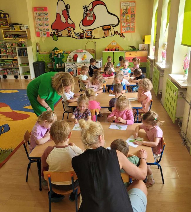 Praca plastyczna. Dzieci przy stolikach kolorują 