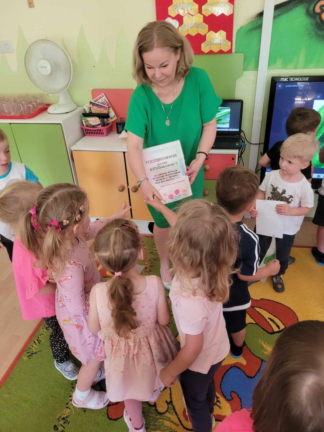 Dzieci siedzą na podłodze, słuchają opowieści