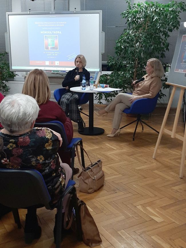 Prowadząca, przy stoliku, prowadzi rozmowę z  autorką Moniką Tadrą 