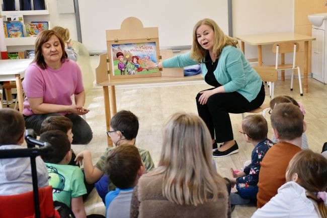 Prowadzące czytają opwoieść metodą teatru kamishibai.