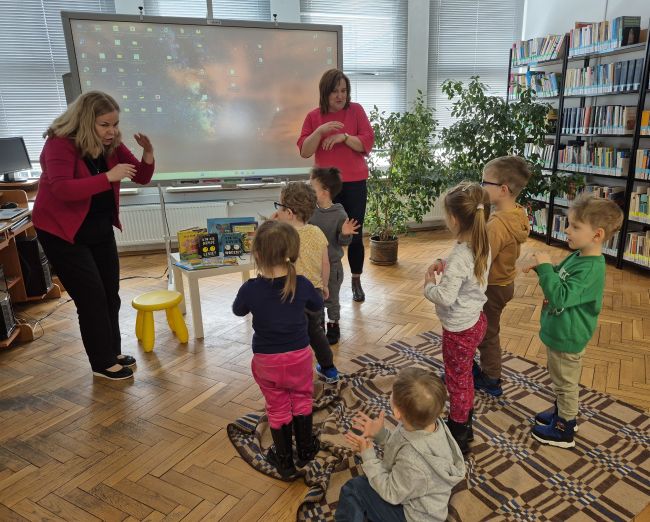 Nauczyciele i dzieci stoją i razem powtarzają zabawę.