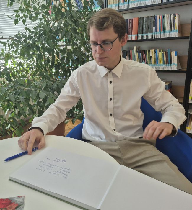 Spotkanie w czytelni Biblioteki Pedagogicznej. Autor Rafał Tadra podpisuje album fotograficzny.