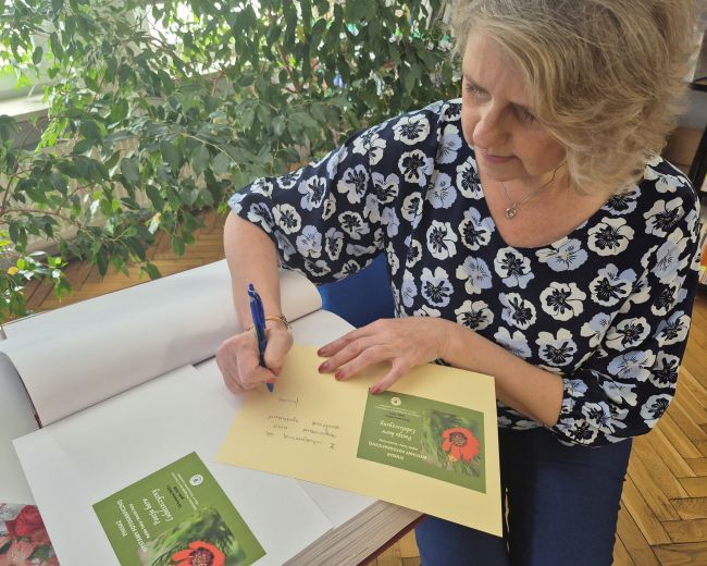 Spotkanie w czytelni Biblioteki Pedagogicznej. Autorka Monika Tadra wpisuje się do kroniki.