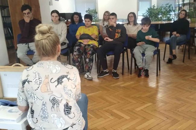 Uczniowie siedzą na krzesłach. Słuchają opowiadania. Inne ujęcie