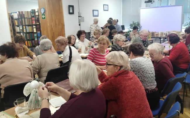 Uczestnicy warsztatów siedzą przy stołach i wykonują prace.