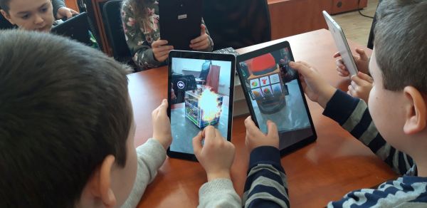 uczniowie oglądają na tabletach kostkę Merge i ukryte w niej obrazki