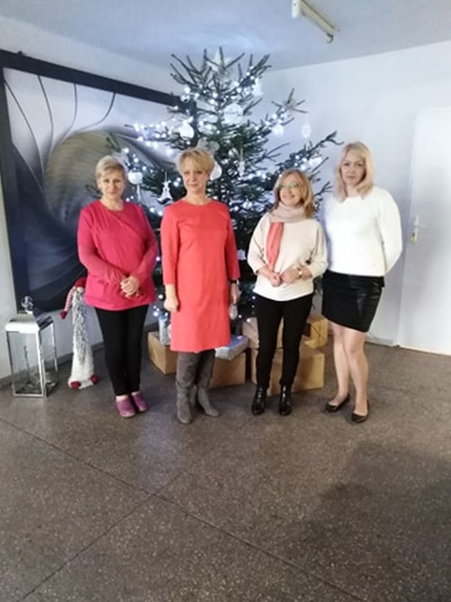 Zapakowane książki w paczkach owinięte ozdobnym i szarym papierem, plakat promujący akcję „Książka na gwiazdkę dla Seniora”, w prawym rogu gwiazda betlejemska.