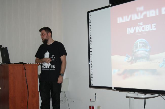 Na zdjęciu widoczny prelegent Artur Harasim przy mównicy w czytelni biblioteki pedagogicznej.