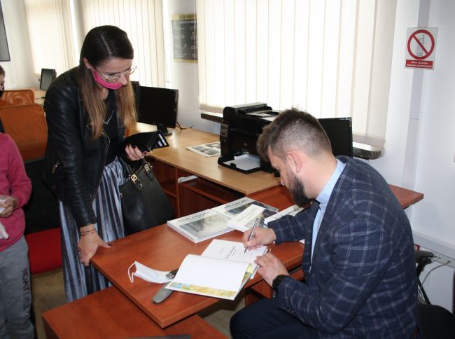 Autor spotkania podpisuje książkę i uczestniczka spotkania