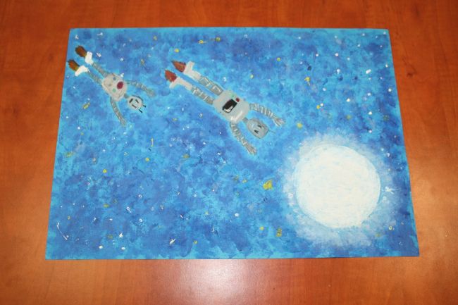 praca plastyczna przedstawiająca planetę i dwa roboty