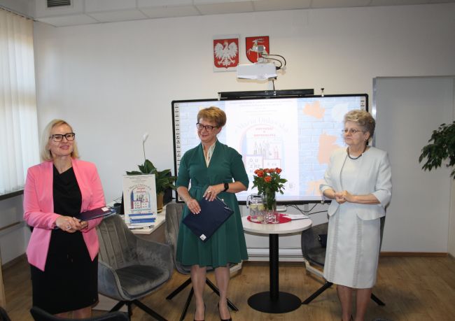 Spotkanie autorskie z Marią Duławską. Zdjęcie pokazuje początek spotkania, widać trzy osobowy. Od lewej: Aneta Bartoszczyk-Trochimiuk, wizytator wizytator Kuratorium Oświaty w Lublinie Delegatura w Zamościu, Dorota Mach, dyrektor Biblioteki Pedagogicznej w Zamościu oraz Maria Duławska, wieloletnia pedagog, autorka książki 