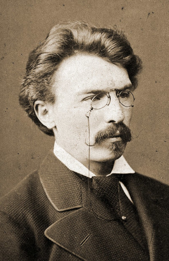 Zdjęcie przedstawia Władysława Bełzę w 1877 roku. Pisarz ujęty jest z profilu. Ma gęste, zaczesane do tyłu włosy oraz sumiaste wąsy. Na nosie małe okrągłe okulary. Ubrany jest w surdut.