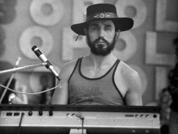 Zdjęcie przedstawia Czesława Niemena podczas Festiwalu w Opolu w 1975 roku. Artysta siedzi przy klawiszach, ma brodę, jest ubrany w podkoszulek, na głowie ma kapelusz.