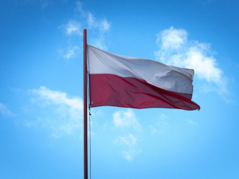 Na zdjęciu widać flagę Polski na maszcie na tle nieba z małymi rozrzedzonymi chmurami.